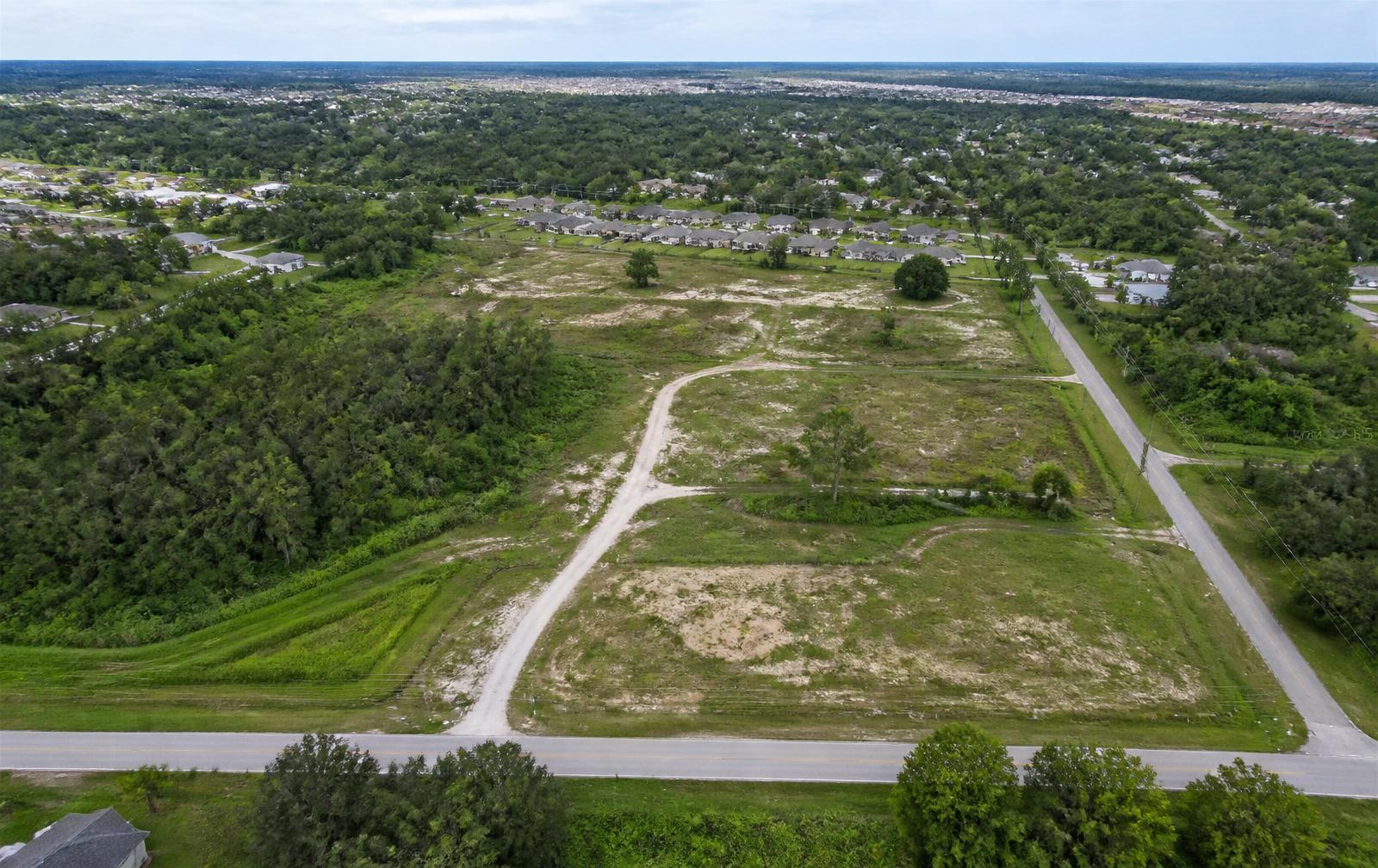 Aerial view of undeveloped parcels with a dirt access road bordering a paved road